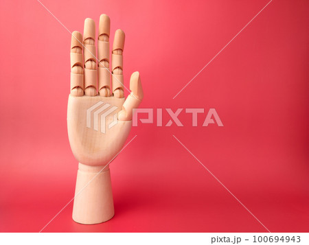 Wooden hand that is showing the style of raising hands on a red background. 100694943