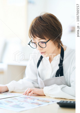 メガネをかけて広告チラシを見る女性 メガネをかけて広告チラシを見る女性 100700557