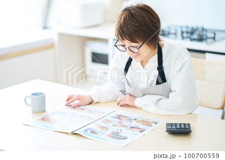 メガネをかけて広告チラシを見る女性 100700559