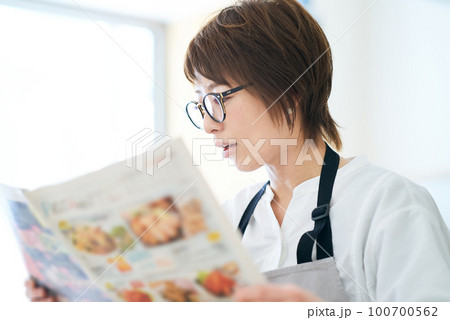 メガネをかけて広告チラシを見る女性 100700562