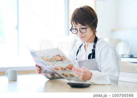 メガネをかけて広告チラシを見る女性 メガネをかけて広告チラシを見る女性 100700566