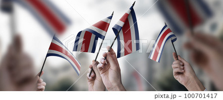 A group of people holding small flags of the Costa Rica in their hands A group of people holding small flags of the Costa Rica in their hands 100701417