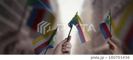 A group of people holding small flags of the Comoros in their hands A group of people holding small flags of the Comoros in their hands 100701436