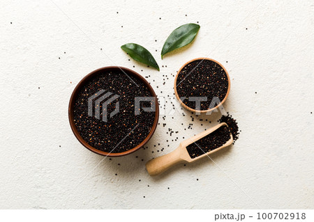 quinoa seeds in bowl and spoon on colored background. Healthy kinwa in small bowl. Healthy superfood quinoa seeds in bowl and spoon on colored background. Healthy kinwa in small bowl. Healthy superfood 100702918