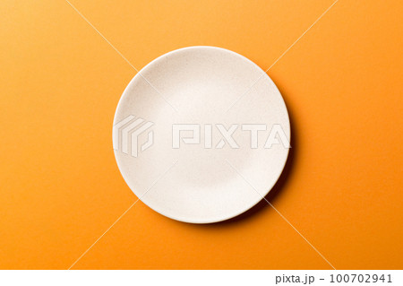 Top view of isolated of colored background empty round beige plate for food. Empty dish with space for your design 100702941