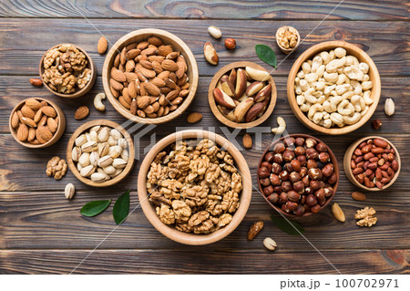 mixed nuts in wooden bowl. Mix of various nuts on colored background. pistachios, cashews, walnuts, hazelnuts, peanuts and brazil nuts 100702971