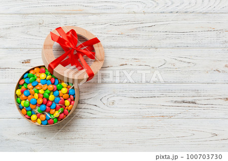 Set of different sweet candy in a paper box with a satin ribbon on a colored background. Holiday concept Set of different sweet candy in a paper box with a satin ribbon on a colored background. Holiday concept 100703730
