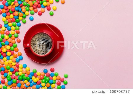Coffee cup with chocolates and colored candy. Top view on table background with copy space 100703757