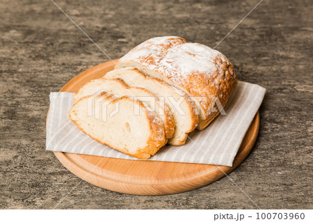 Assortment of freshly sliced baked bread with napkin on rustic table top view. Healthy unleavened bread. French bread slice 100703960
