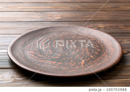 Perspective view of empty black plate on wooden background. Empty space for your design 100703988