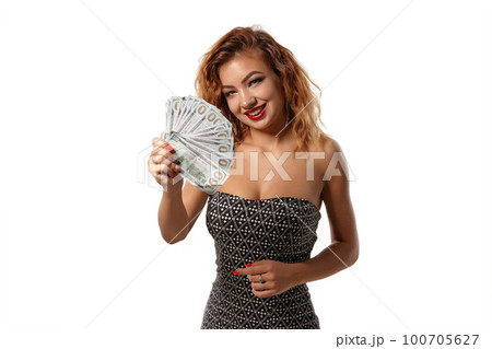 Ginger girl in gray dress posing holding fan of hundred-dollar bills while standing isolated on white background. Casino, poker. Close-up shot. Ginger girl in gray dress posing holding fan of hundred-dollar bills while standing isolated on white background. Casino, poker. Close-up shot. 100705627