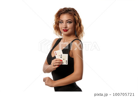 Ginger girl wearing a black dress is posing holding two playing cards in her hands standing isolated on white background. Casino, poker. Close-up. Ginger girl wearing a black dress is posing holding two playing cards in her hands standing isolated on white background. Casino, poker. Close-up. 100705721