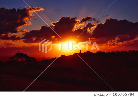 Dramatic sunset scene over hills in the countryside with deep shades of orange, red and blue Dramatic sunset scene over hills in the countryside with deep shades of orange, red and blue 100705794