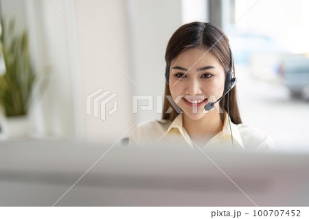 Portrait of happy smiling female customer support phone operator at workplace. Smiling beautiful Asian woman working in call center 100707452