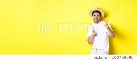 Concept of tourism and vacation. Happy cool guy pointing fingers at you, standing over yellow background 100708096