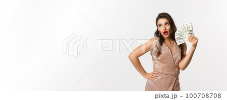 Shopping concept. Successful attractive woman in elegant dress showing dollars, bragging with money, standing over white background Shopping concept. Successful attractive woman in elegant dress showing dollars, bragging with money, standing over white background 100708708