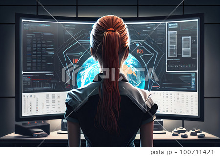 view from back to female student sitting at desk in front of monitor. 100711421