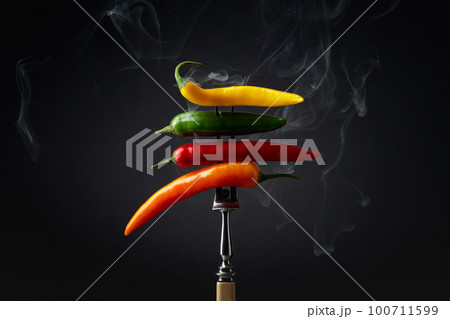 Hot chili peppers with smoke on a black background. Hot chili peppers with smoke on a black background. 100711599