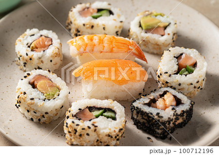 Closeup homemade sushi rolls with salmon, shrimp, avocado i n a round plate 100712196