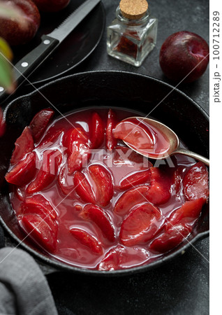 Red plums confiture, jam or fruit sauce in black frying pan. Red plums confiture, jam or fruit sauce in black frying pan. 100712289