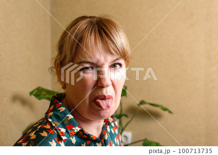 Woman procrastinate at home workplace. Playful woman sticking out tongue in office. Funny face concept. Businesswoman sticking out her tongue and showing. Out of focus 100713735