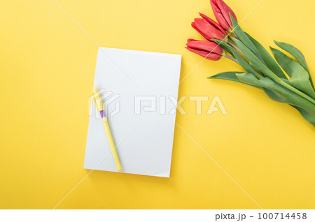 Top view of yellow desk with blank notebooks mockup with pencil and tulips. notebook 100714458
