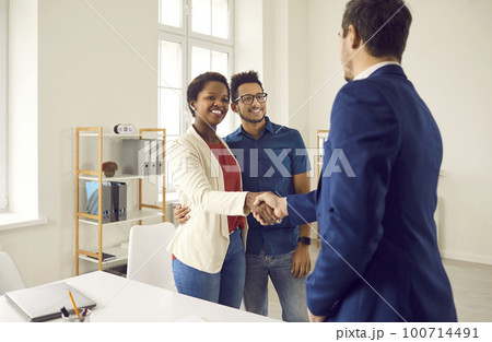 Happy black couple meeting and shaking hands with realtor, loan broker or insurance advisor Happy black couple meeting and shaking hands with realtor, loan broker or insurance advisor 100714491