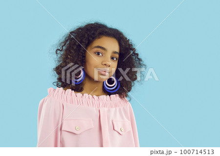Portrait of cute pretty dark-skinned curly preteen girl isolated on light blue background. 100714513