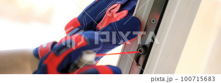 Handyman in gloves puffs liquid on pvc window clamps closeup Handyman in gloves puffs liquid on pvc window clamps closeup 100715683