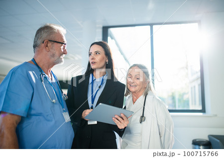 Young pharmaceutic seller explaining something to doctors in hospital. Young pharmaceutic seller explaining something to doctors in hospital. 100715766