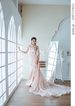 asian bride standing between the window and the mirror asian bride standing between the window and the mirror 100715923