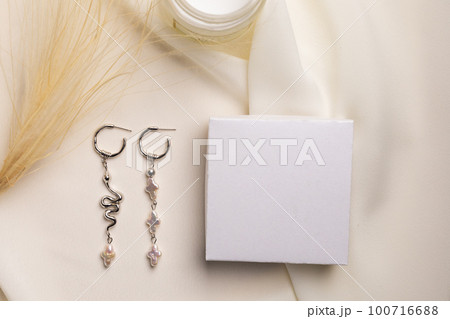 Elegant jewelry set of silver earrings with gem and gift box mock up copy space. Jewelry set minimalist style. Handmade bijouterie concept. 100716688