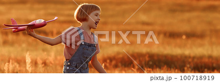 Child launches a toy plane in the field Child launches a toy plane in the field 100718919