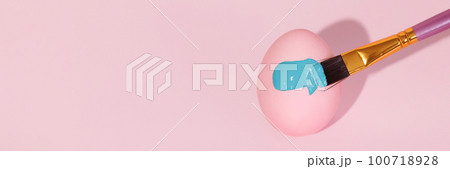 The brush paints with blue gouache a pink Easter egg The brush paints with blue gouache a pink Easter egg 100718928