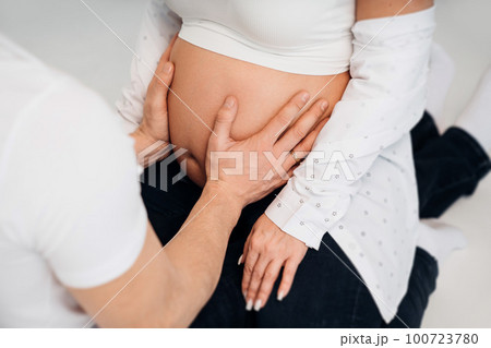 a man's hand on the stomach of a pregnant woman. a man's hand on the stomach of a pregnant woman. 100723780