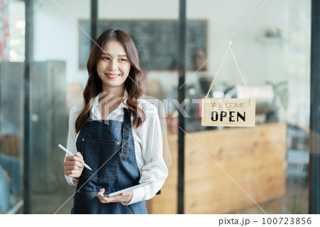 open a small business Portrait of happy Asian woman in apron holding tablet in front of cafe open a small business Portrait of happy Asian woman in apron holding tablet in front of cafe 100723856