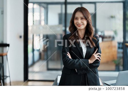 Portrait of a woman business owner showing a happy smiling face as he has successfully invested her business using computers and financial budget documents at work. Portrait of a woman business owner showing a happy smiling face as he has successfully invested her business using computers and financial budget documents at work. 100723858