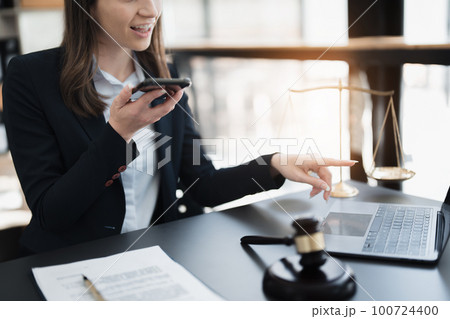 Portrait of a Asian woman lawyer studying lawsuit a for a client using smartphone , documents and computer to work before going to court 100724400