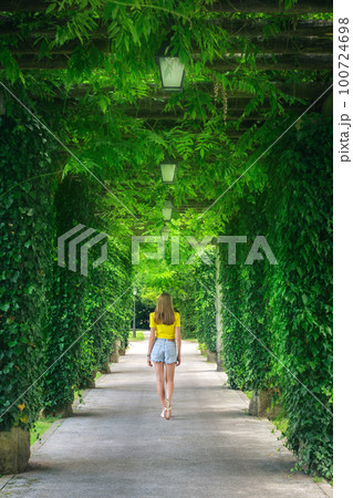 Green trees alley and young woman in blooming park in summer 100724698