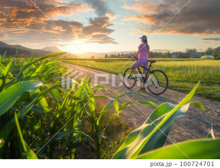 Woman on mountain bike on gravel road at sunset in summer 100724701