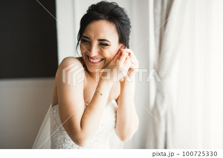 Beautiful bride wearing fashion wedding dress with feathers with luxury delight make-up and hairstyle, studio indoor photo shoot Beautiful bride wearing fashion wedding dress with feathers with luxury delight make-up and hairstyle, studio indoor photo shoot 100725330