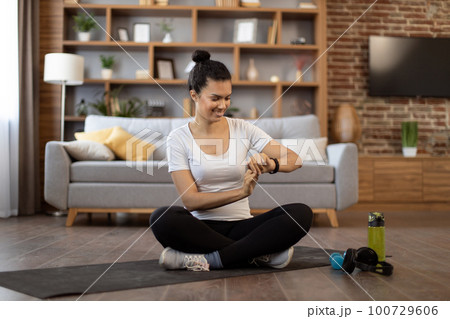 Lady monitoring workout achievements on smartwatch at home 100729606