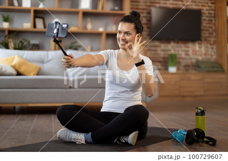 Young coach live streaming fitness tutorial via cell phone Young coach live streaming fitness tutorial via cell phone 100729607