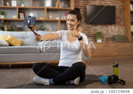 Young coach live streaming fitness tutorial via cell phone Young coach live streaming fitness tutorial via cell phone 100729608