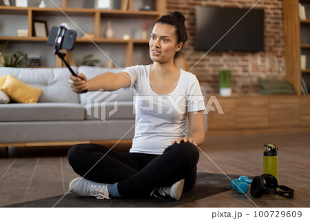 Young coach live streaming fitness tutorial via cell phone 100729609