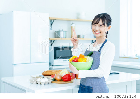 キッチンでサラダボウルを持つ若い女性 100733124