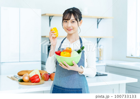 キッチンでサラダボウルを持つ若い女性 100733133