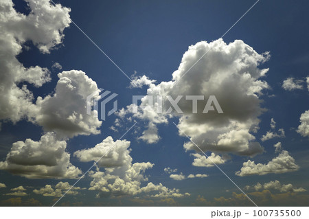 White puffy cumulus clouds on summer blue sky 100735500