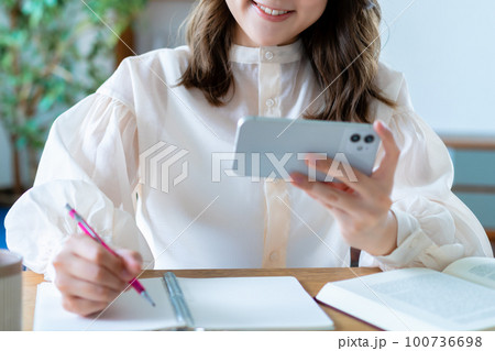 スマホの動画を観て勉強する女性【パーツカット】 100736698