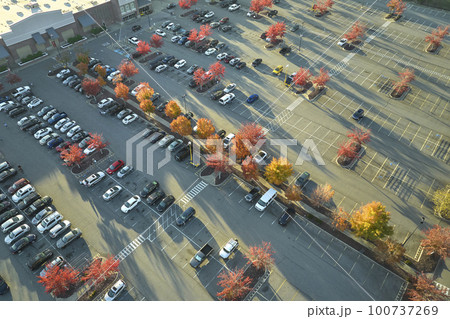 View from above of american grocery store with many parked cars on parking lot with lines and markings for parking places and directions. Place for vehicles in front of a strip mall center 100737269